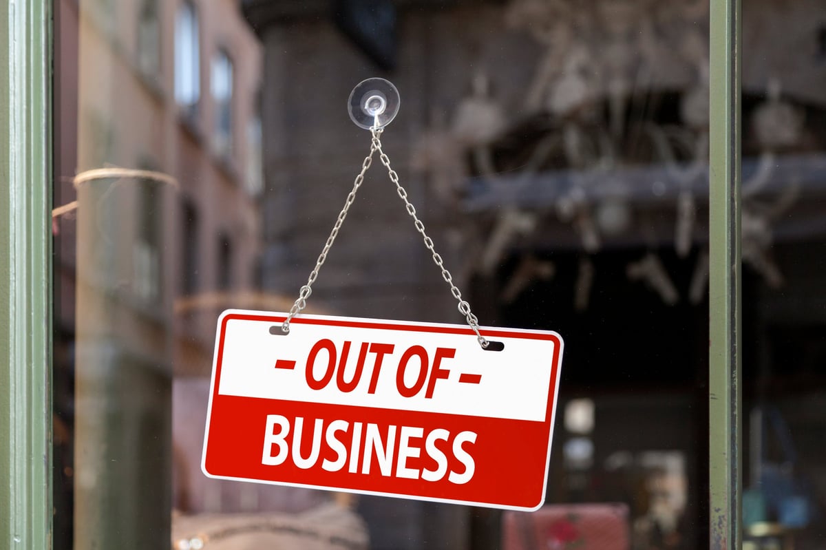 Close-up on a red sign in a window written inside in English 'Out of business'.
