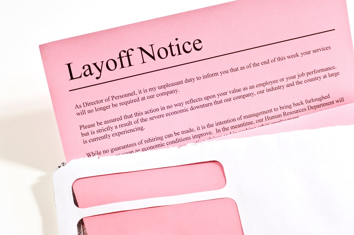 Close-up of layoff notice or pink slip in opened envelope.