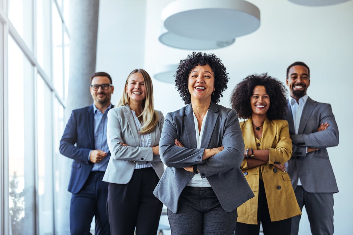 A diverse group of business professionals smiling confidently in a modern office environment
