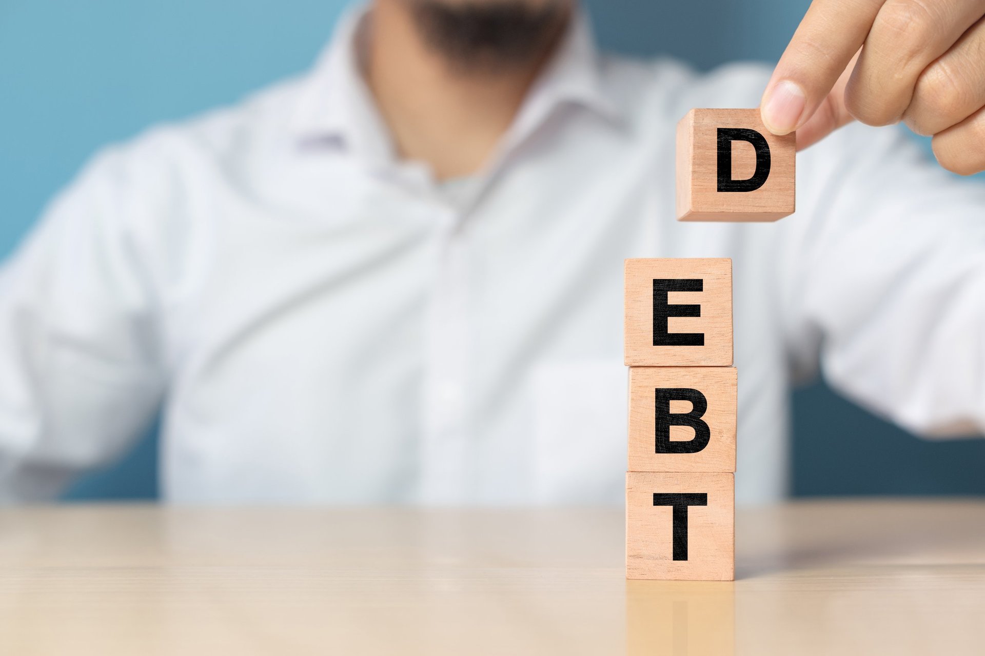 Businessman removes wooden blocks with the word Debt. Reduction or restructuring of debt. Bankruptcy announcement. Refusal to pay debts or loans and invalidate them