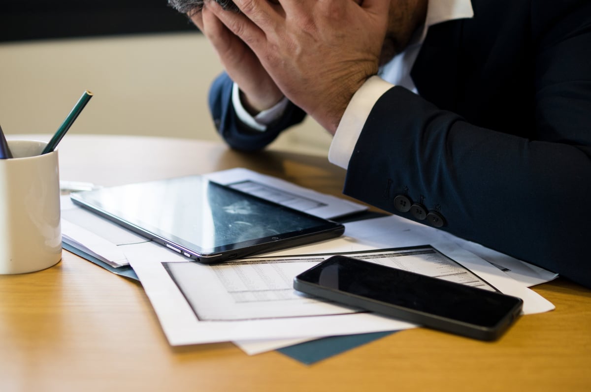 UK business director under financial stress at a desk reviewing bills and invoices, deciding which creditors to pay first