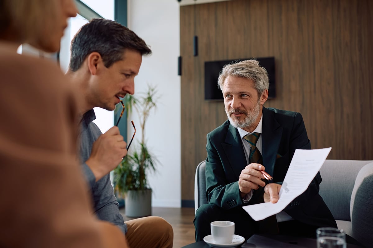 Smiling insurance agent analyzing financial reports with a couple on a meeting in the office.