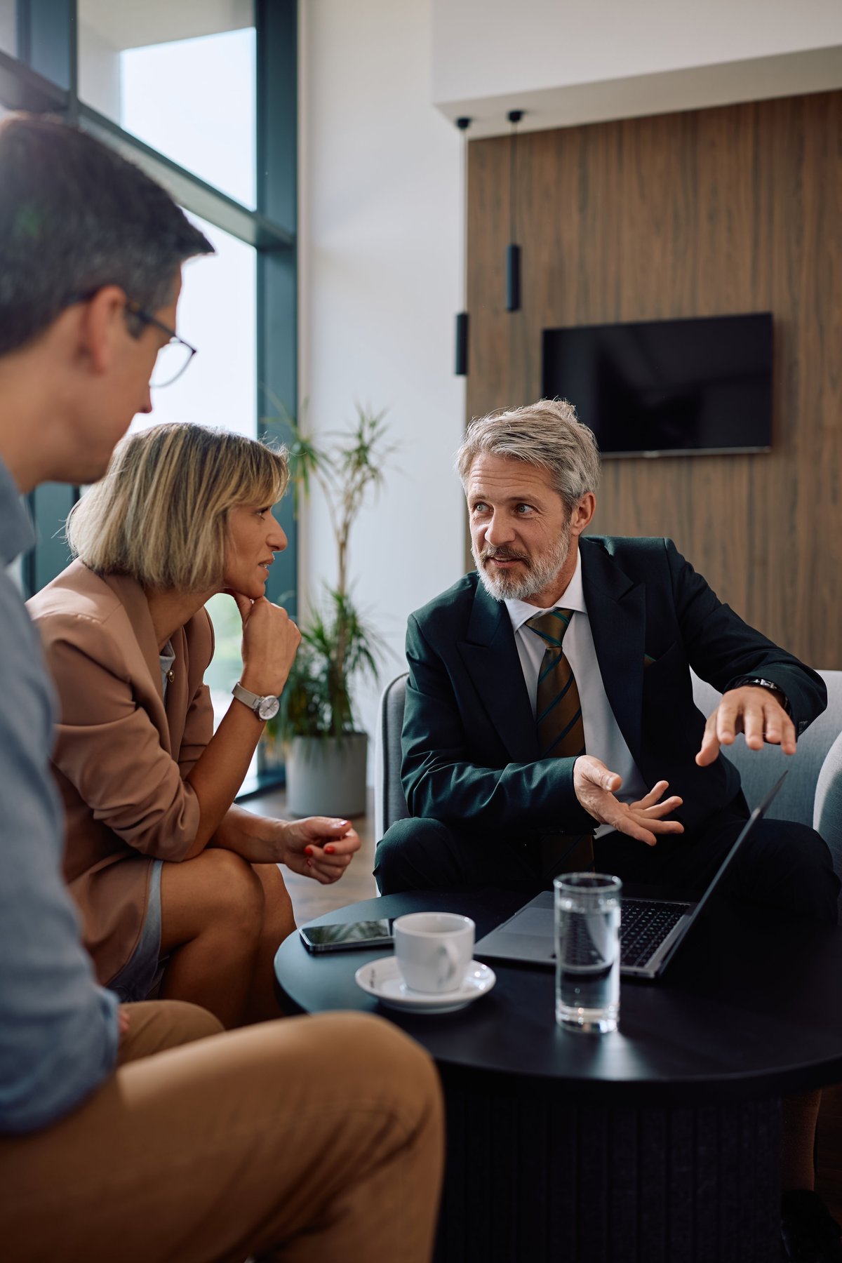 Mature financial advisor using laptop while talking to a couple during the meeting.
